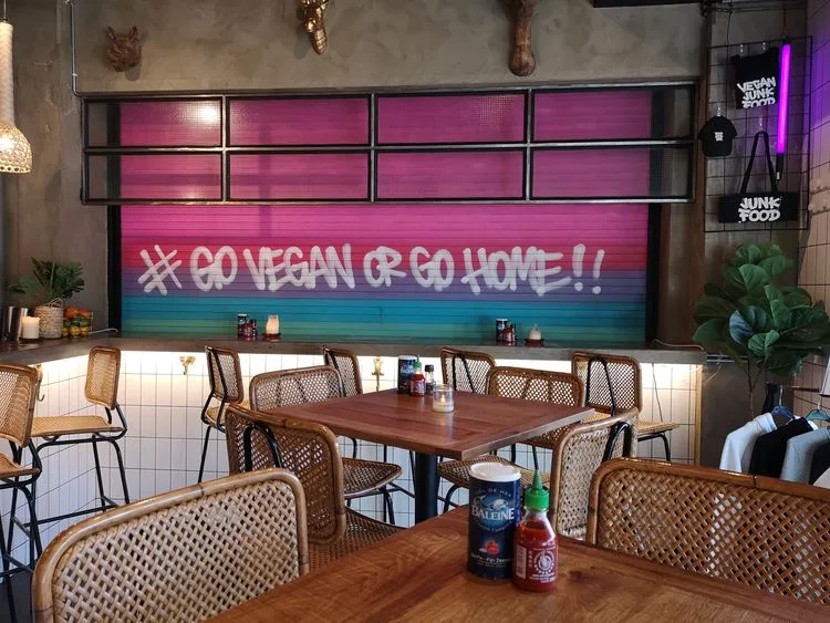 Een restaurant met op de achtergrond een kleurrijke queote #goveganorgohome